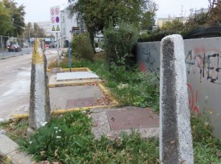 Stari betonski stupovi koji su branili promet i parkiranje na zelenoj površini uz pumpu su još tamo. [VR 2025.]